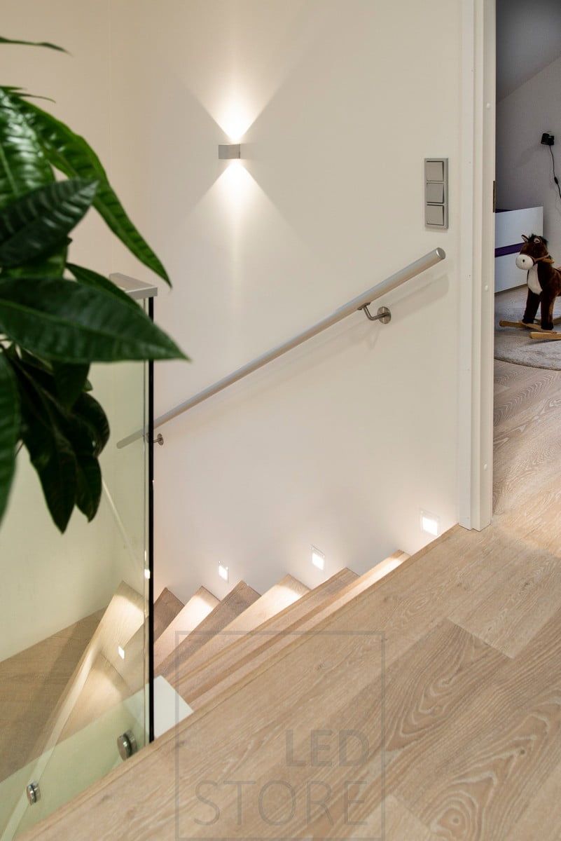 Staircase lighting, with a step lamp at every second step and bi-directional luminaires on the wall.